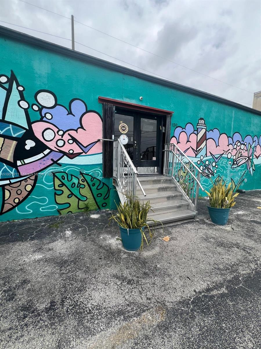 A teal building exterior features a mural, a metal staircase, and two potted plants — 139 NE 1st Ave, Hallandale Beach FL 33009, HALLANDALE BEACH, FL