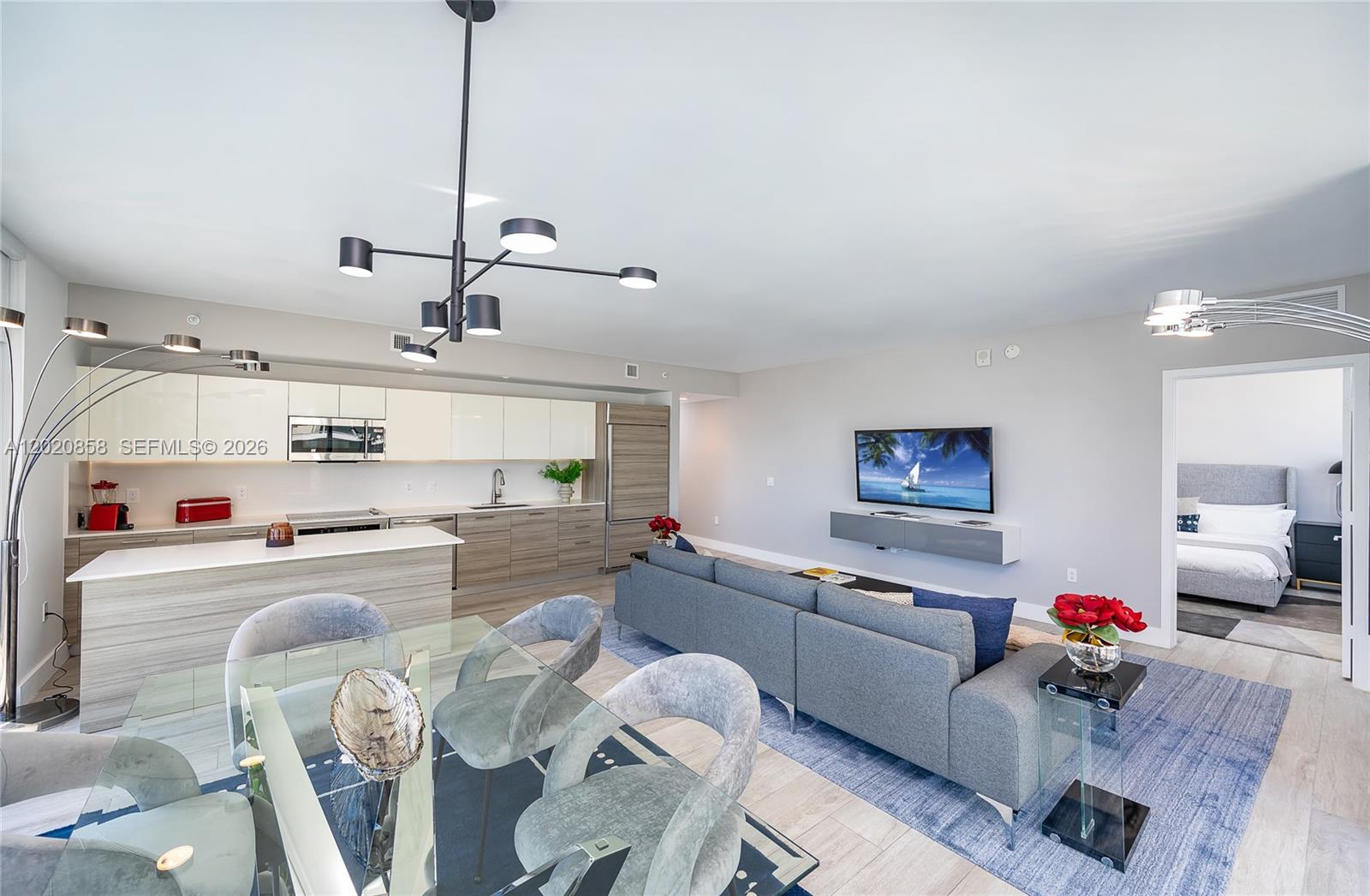 An open-concept living area features a modern kitchen, dining space, and a gray sectional sofa — 121 NE 34th St # 1408, Miami FL 33137, MIAMI, FL