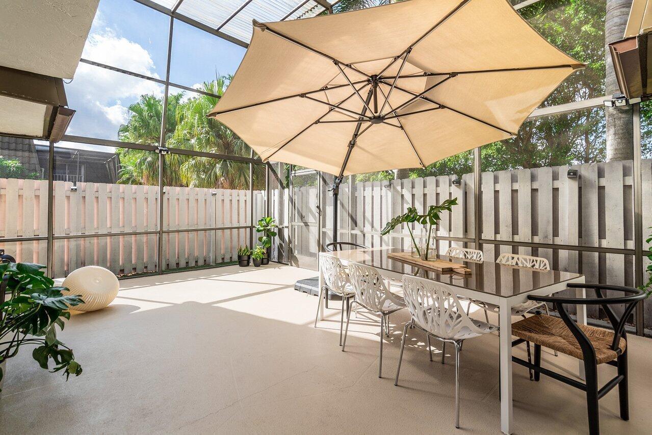 A screened-in patio features a dining set under a large umbrella and a fenced yard — 22184 Boca Rancho Drive # A, Boca Raton FL 33428, BOCA RATON, FL