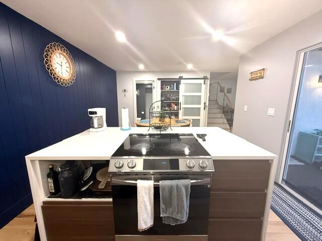 A kitchen island with a built-in stove sits before a dark blue accent wall — 22184 Boca Rancho Drive # A, Boca Raton FL 33428, BOCA RATON, FL
