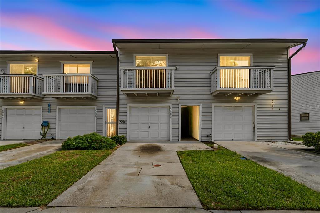 A two-story townhouse exterior features three garage doors, second-story balconies, and a concrete driveway — 6437 93RD TERRACE N UNIT 5002, PINELLAS PARK, FL