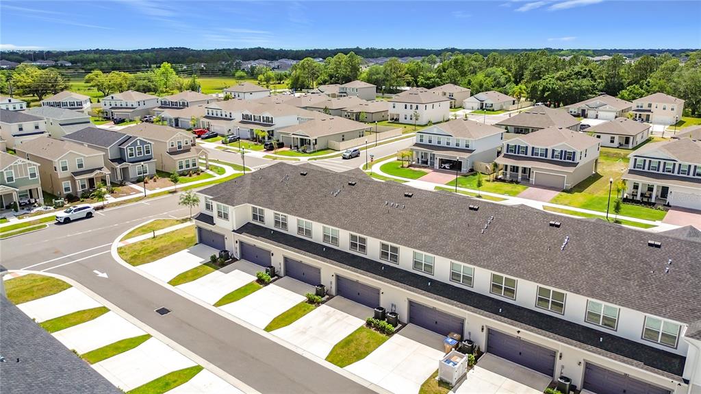 An aerial view shows a row of townhomes with attached garages and surrounding suburban houses — 371 CROSSINGS AVENUE, ST CLOUD, FL