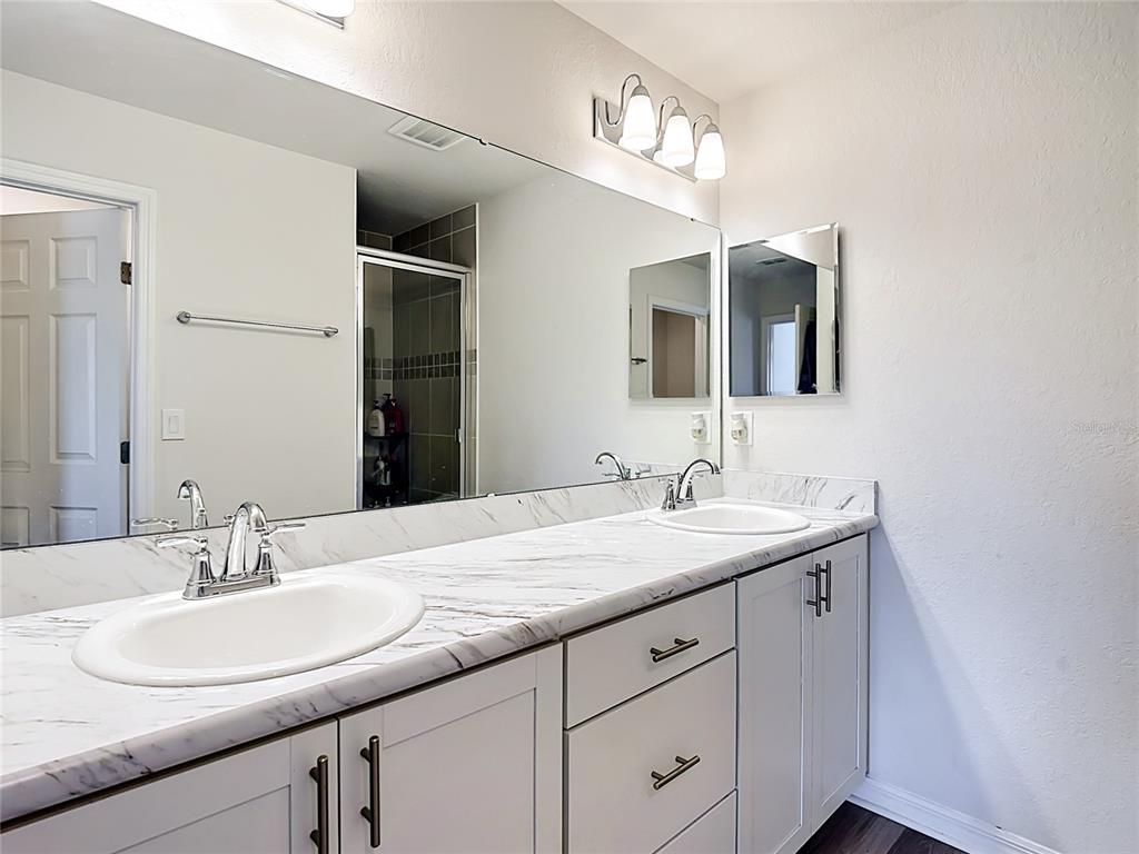 A bathroom features a double-sink vanity with a marble-look countertop and gray cabinetry — 371 CROSSINGS AVENUE, ST CLOUD, FL