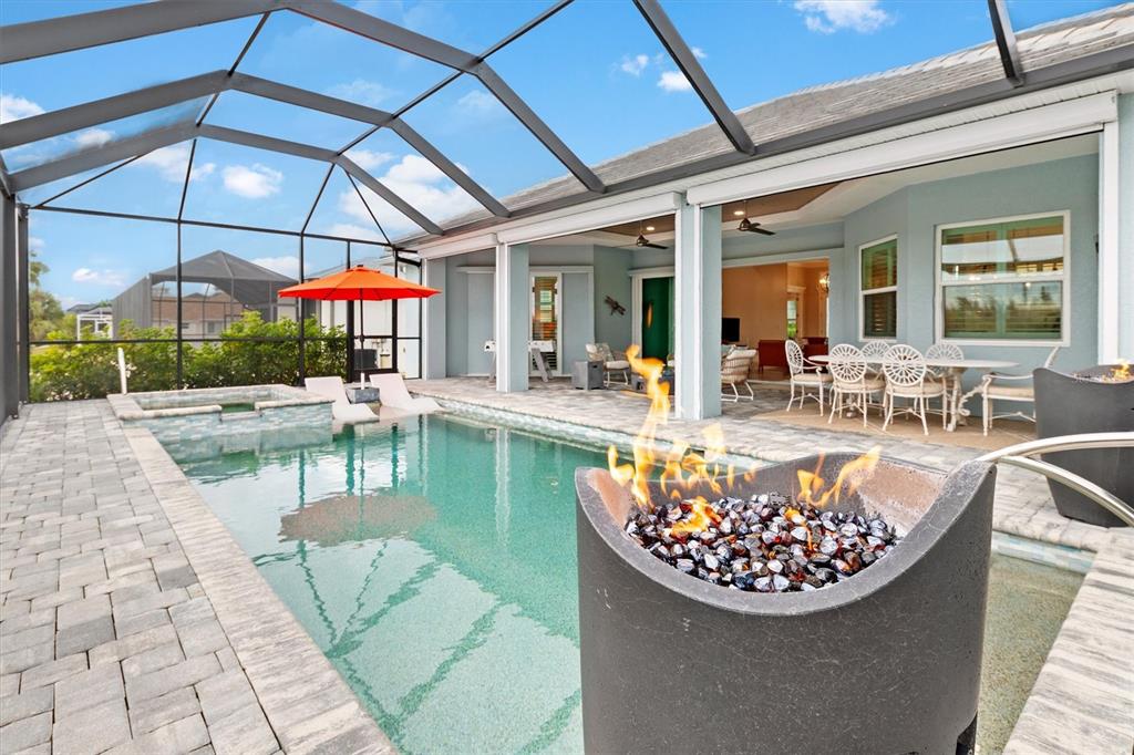 A screened-in patio features a swimming pool, a fire pit, and outdoor dining furniture — 15650 MEACHAM CIRCLE, PORT CHARLOTTE, FL