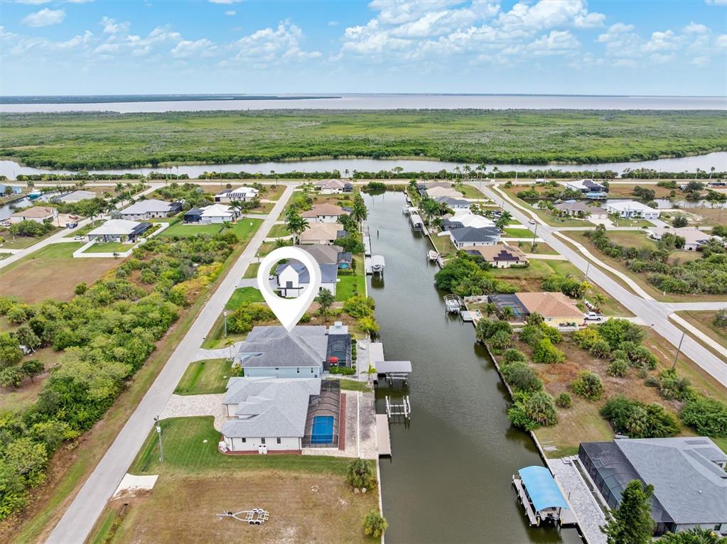 An aerial view shows a waterfront house with a pool and boat dock — 15650 MEACHAM CIRCLE, PORT CHARLOTTE, FL