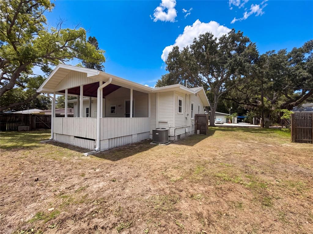The exterior of a light-colored house features a screened-in porch and an air conditioning unit — 345 ACROPOLIS DRIVE, DUNEDIN, FL