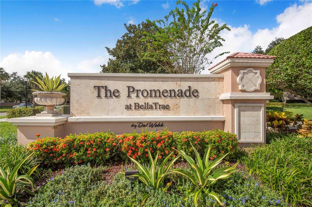 A stone monument sign for The Promenade at BellaTrae sits amidst landscaped greenery and plants — 1206 ROMANI AVENUE, DAVENPORT, FL