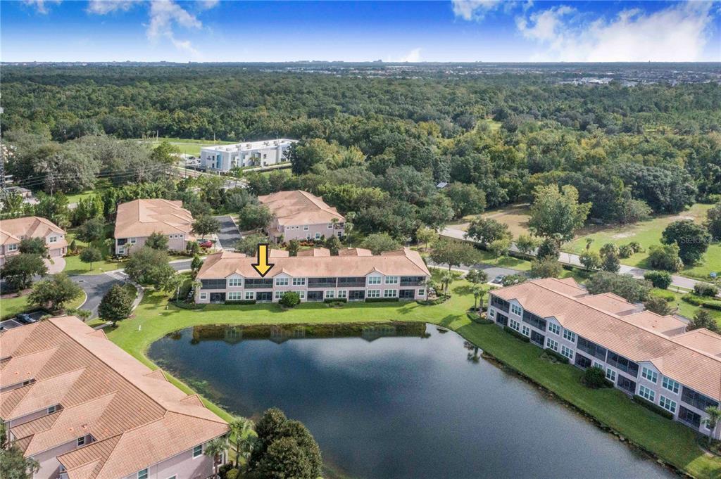 An aerial view of a multi-story apartment building situated next to a pond — 1206 ROMANI AVENUE, DAVENPORT, FL
