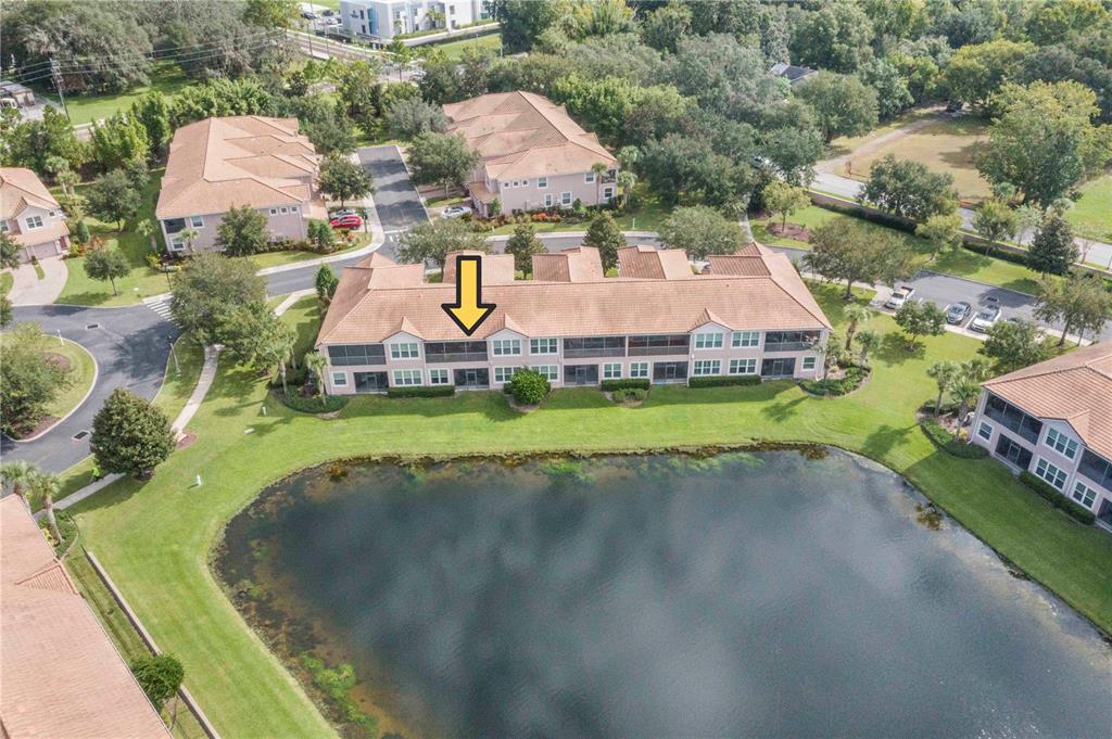 An aerial view shows a multi-story residential building with a screened balcony facing a pond — 1206 ROMANI AVENUE, DAVENPORT, FL