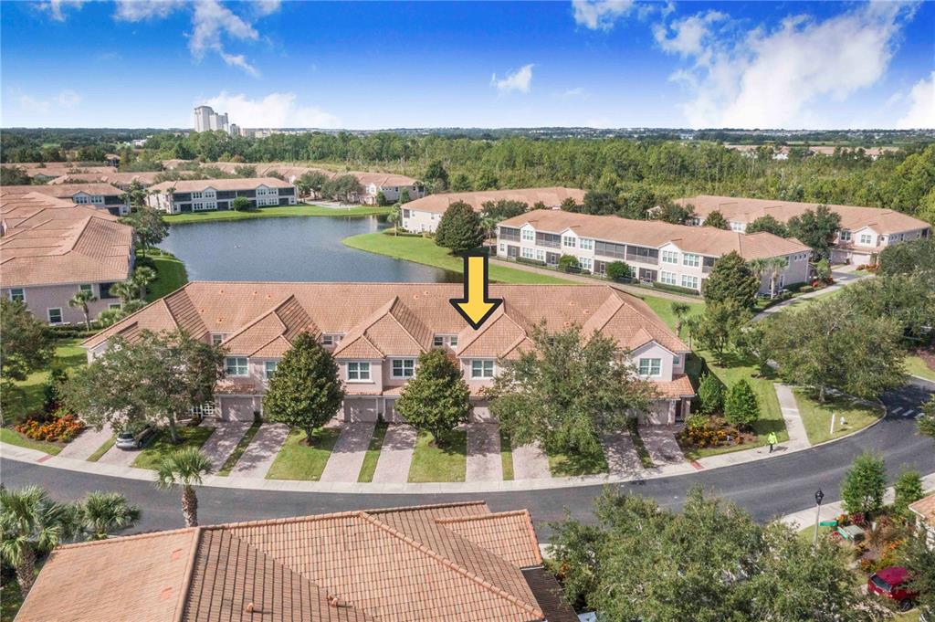 An aerial view shows a row of townhouses with tile roofs near a small lake — 1206 ROMANI AVENUE, DAVENPORT, FL