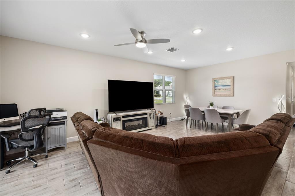 This open-concept living area features a large brown sectional, a dining set, and a desk — 1060 RIVER OTTER WAY, DELAND, FL