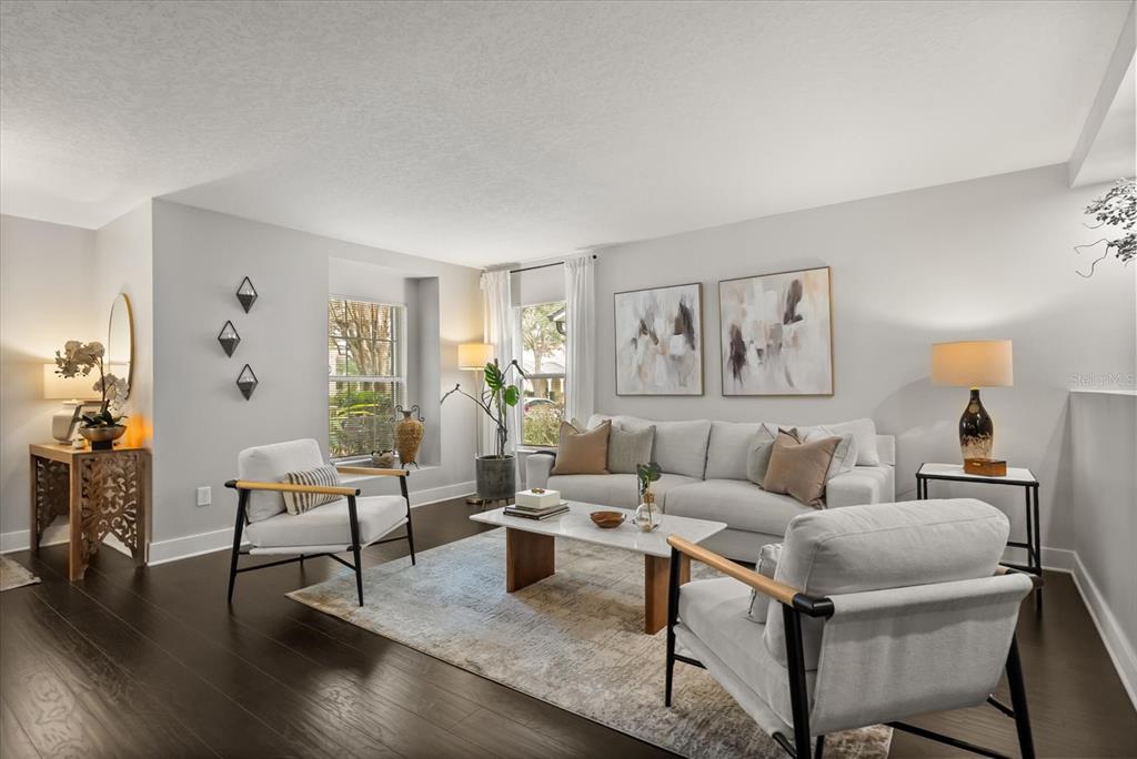 A living room features a white sofa, two armchairs, a coffee table, and dark flooring — 13850 CAROLINA LAUREL DRIVE, ORLANDO, FL