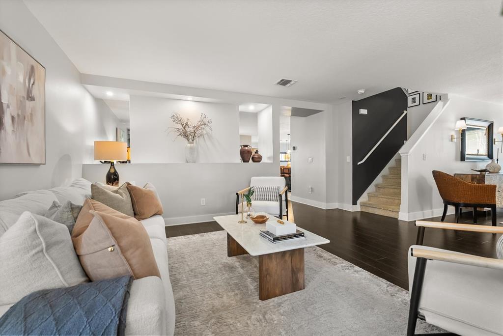 A living room features a white sofa, marble coffee table, and stairs with dark walls — 13850 CAROLINA LAUREL DRIVE, ORLANDO, FL