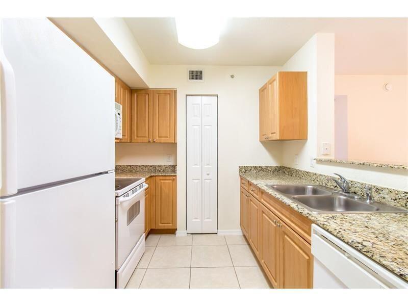 A kitchen with light wood cabinets, granite countertops, white appliances, and beige tile flooring — 6760 Heritage # 6103, Boynton Beach FL 33437, BOYNTON BEACH, FL