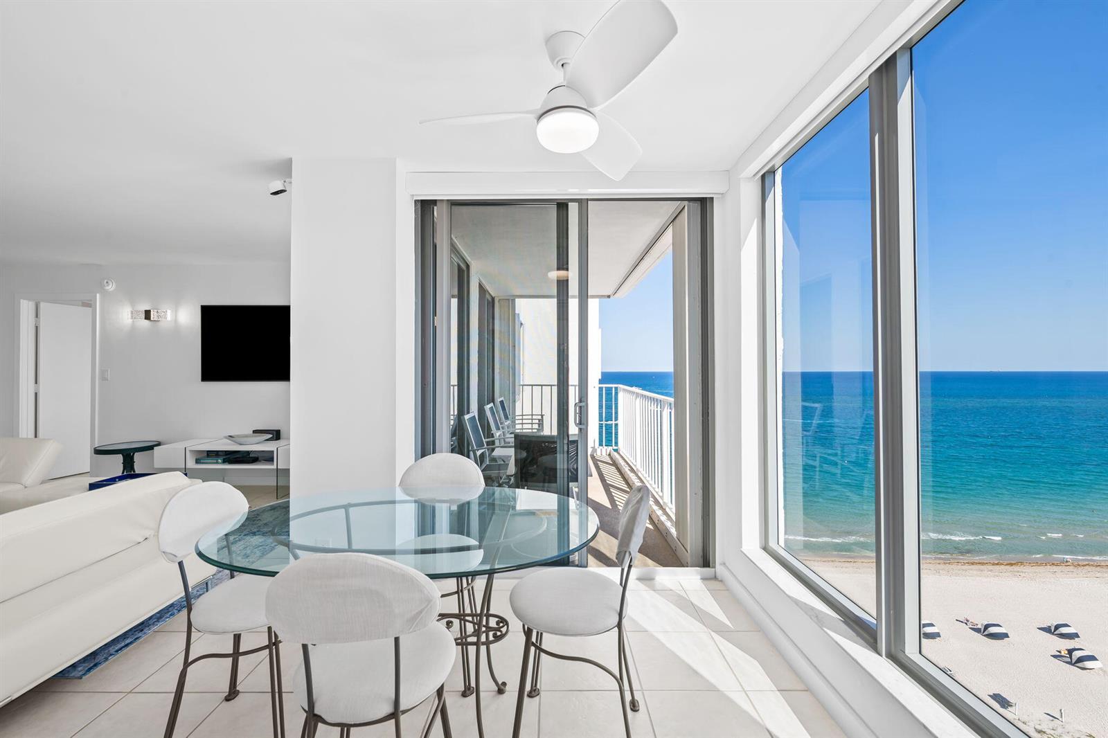 A dining area with a glass table and chairs overlooks a balcony and the ocean — 1010 S Ocean Boulevard # 1502, Pompano Beach FL 33062, POMPANO BEACH, FL