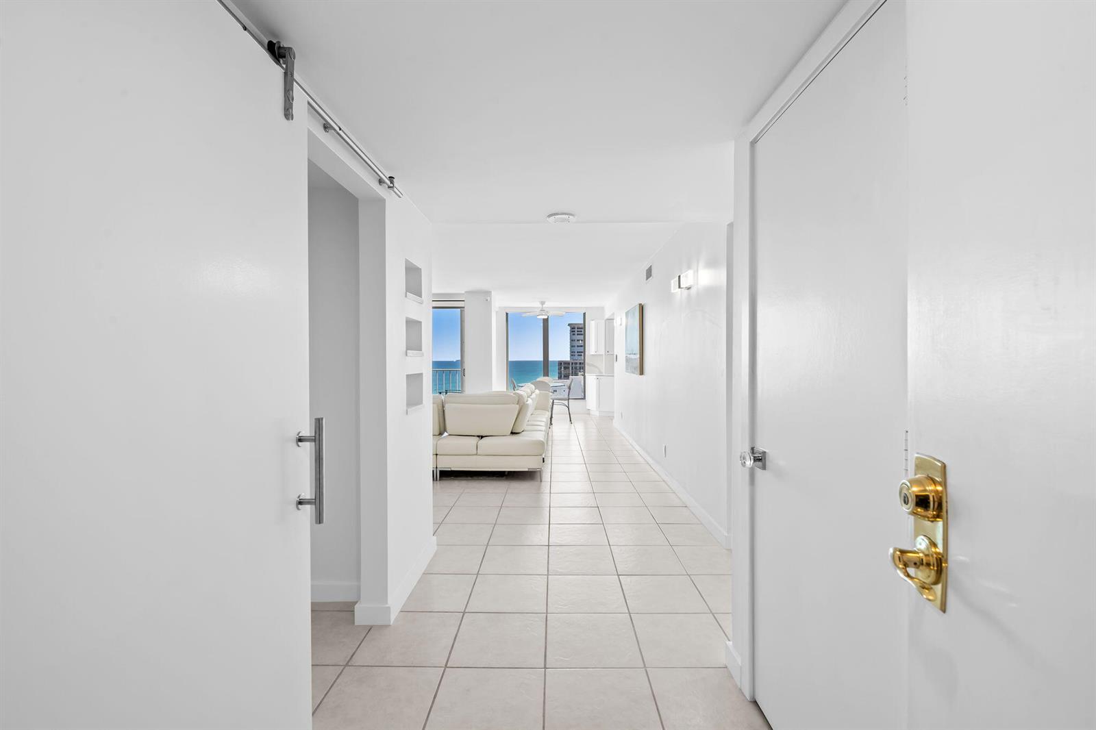 A view from an entryway looking down a tiled hallway toward a bright living area — 1010 S Ocean Boulevard # 1502, Pompano Beach FL 33062, POMPANO BEACH, FL