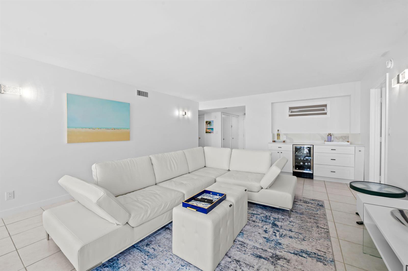 A white sectional sofa and ottoman sit on a blue patterned rug in a living room — 1010 S Ocean Boulevard # 1502, Pompano Beach FL 33062, POMPANO BEACH, FL
