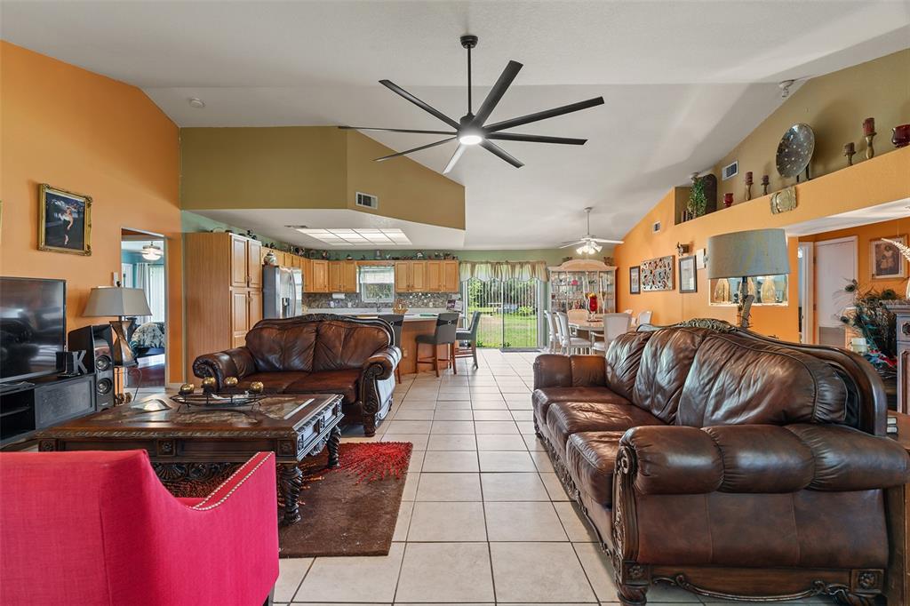 An open-concept living area features tile floors, leather sofas, and a large ceiling fan — 2830 HORTON RD, KISSIMMEE, FL