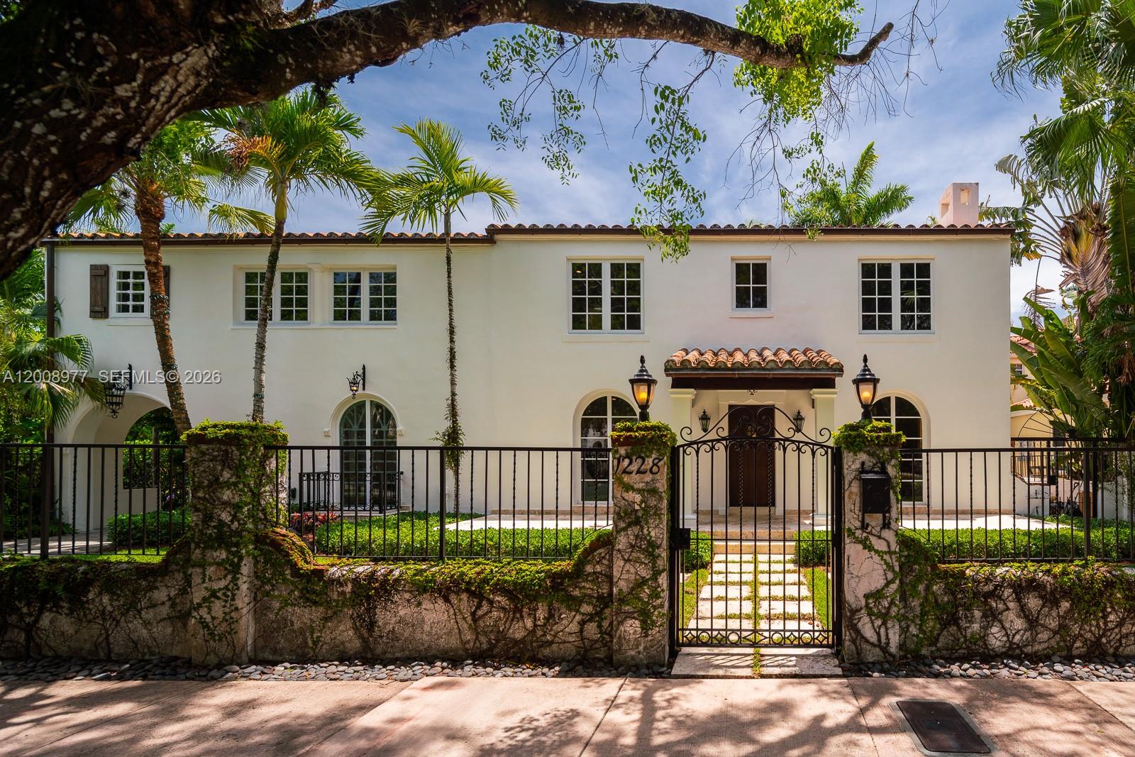 A white two-story house overlooks a rectangular swimming pool with a hot tub and patio — 1228 Alhambra Cir, Coral Gables FL 33134, CORAL GABLES, FL