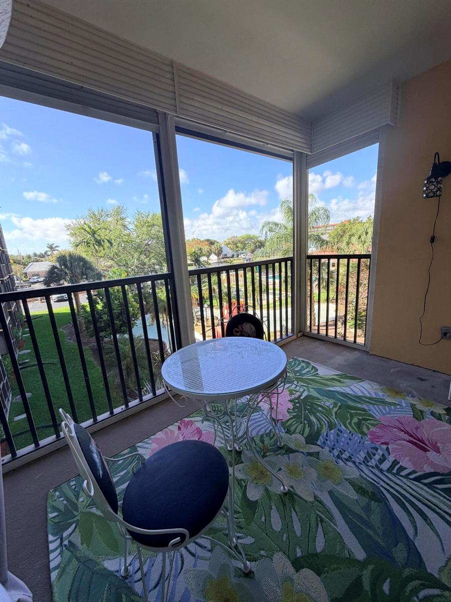 A living and dining area features wood-look flooring, a wicker coffee table, and sliding glass doors — 2601 NE 14th Street # 340, Pompano Beach FL 33062, POMPANO BEACH, FL