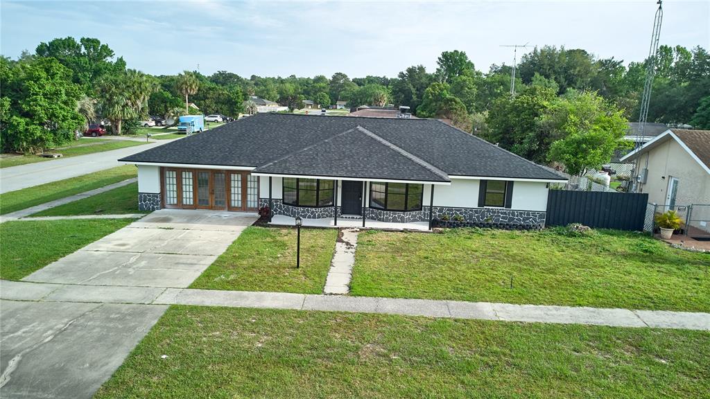 An exterior view of a single-story house with a dark roof and stone-accented facade — 211 MARION OAKS LANE, OCALA, FL
