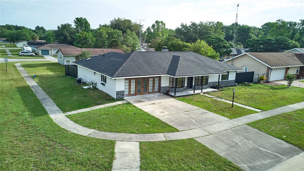 An aerial view of a single-story house with a dark roof and a concrete driveway — 211 MARION OAKS LANE, OCALA, FL