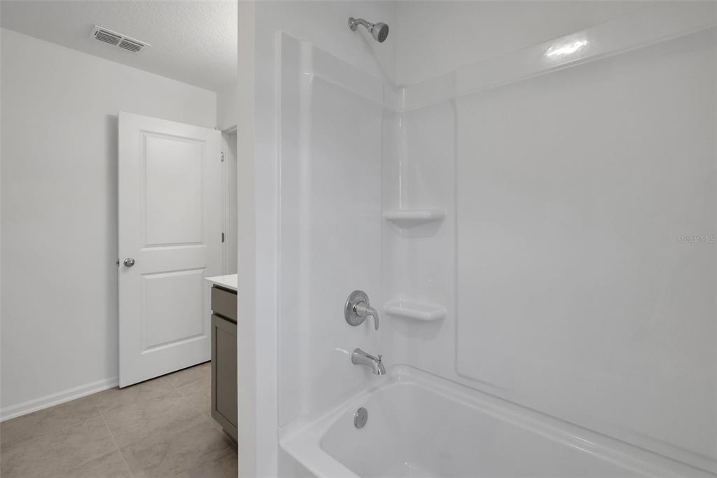 A white bathtub and shower surround with chrome fixtures next to a bathroom doorway — 14367 FIREBIRD DRIVE, JACKSONVILLE, FL