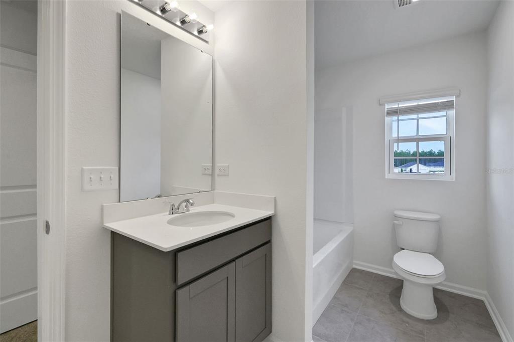 A bathroom features a gray vanity with a white countertop, a mirror, and a tub-shower — 14367 FIREBIRD DRIVE, JACKSONVILLE, FL