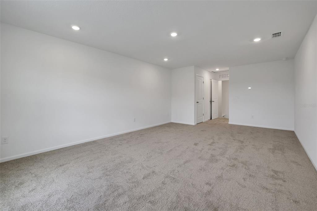 A spacious, empty room features white walls, recessed ceiling lights, and wall-to-wall carpeting — 14367 FIREBIRD DRIVE, JACKSONVILLE, FL