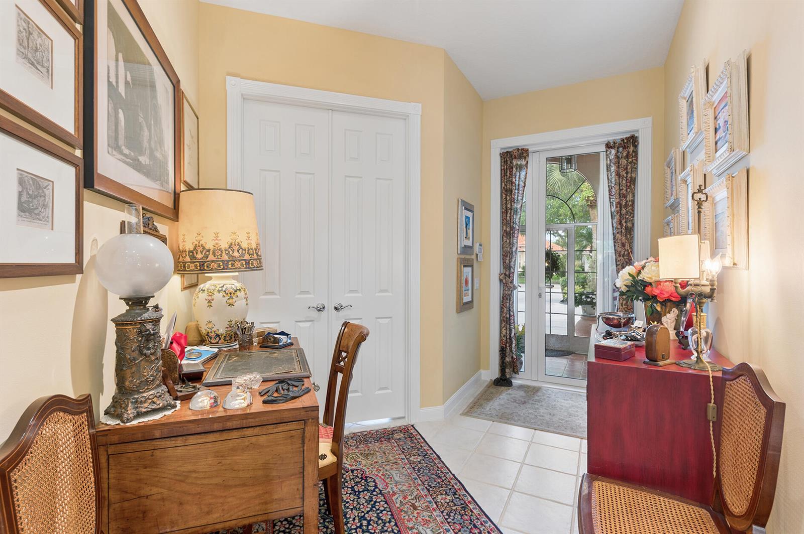 A foyer features a wooden desk, a red cabinet, and a glass door to the outside — 2525 Kittbuck Way, West Palm Beach FL 33411, WEST PALM BEACH, FL