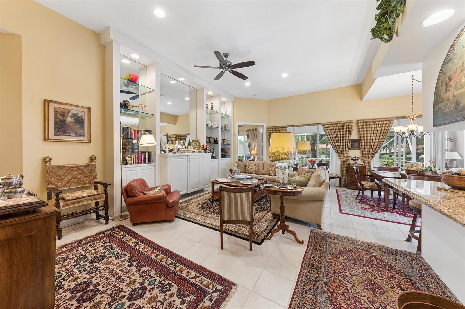 A living room features tile floors, area rugs, built-in shelving, and a vaulted ceiling — 2525 Kittbuck Way, West Palm Beach FL 33411, WEST PALM BEACH, FL