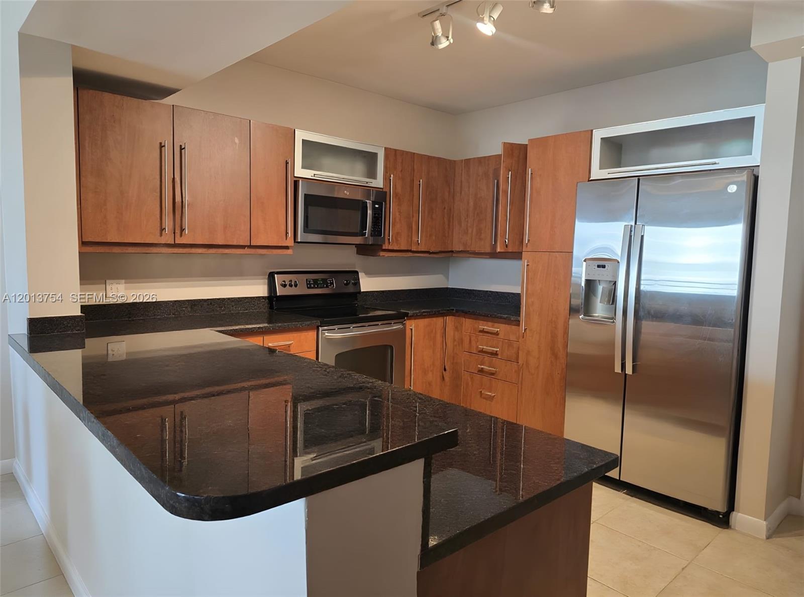 A kitchen features wood cabinets, dark granite countertops, and stainless steel appliances — 7350 SW 89th St # 1506S, Miami FL 33156, MIAMI, FL