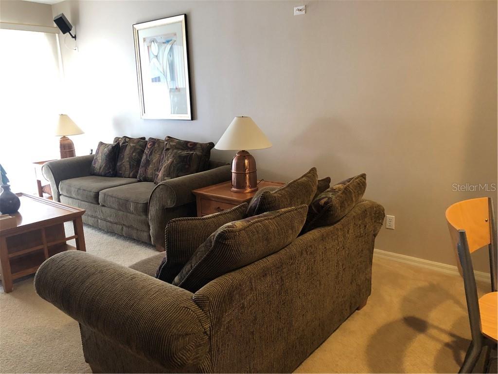 A living room features two brown fabric sofas, a wooden coffee table, and table lamps — 1838 SAN SILVESTRO DRIVE, VENICE, FL