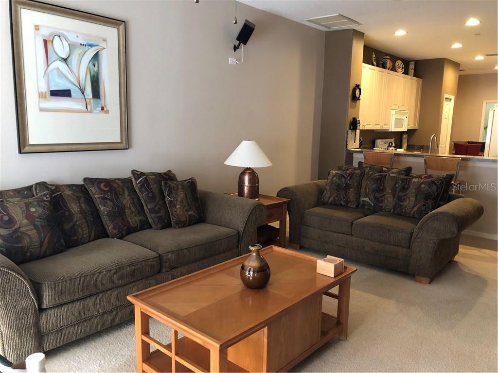 A living room features two brown sofas, a wooden coffee table, and an open kitchen — 1838 SAN SILVESTRO DRIVE, VENICE, FL