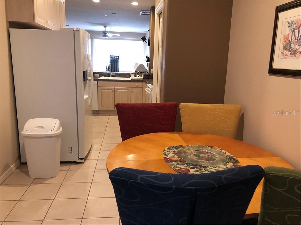 A dining area with a round wooden table and colorful chairs sits beside a kitchen — 1838 SAN SILVESTRO DRIVE, VENICE, FL