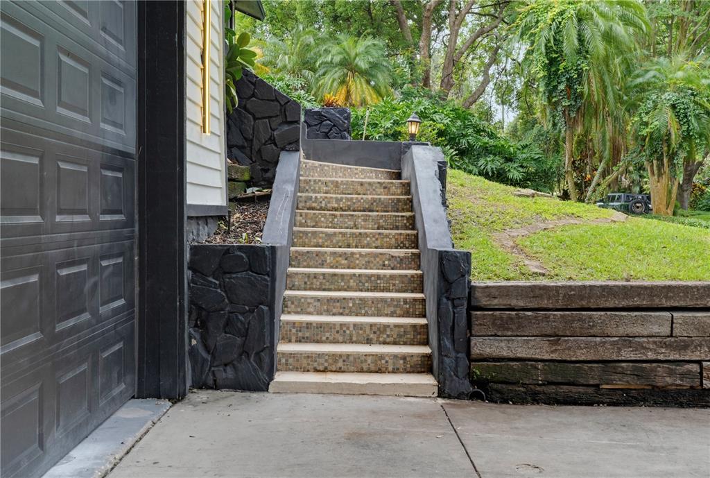 A set of tiled outdoor stairs leads up a grassy embankment next to a garage — 17 PINEWOOD CIRCLE, SAFETY HARBOR, FL