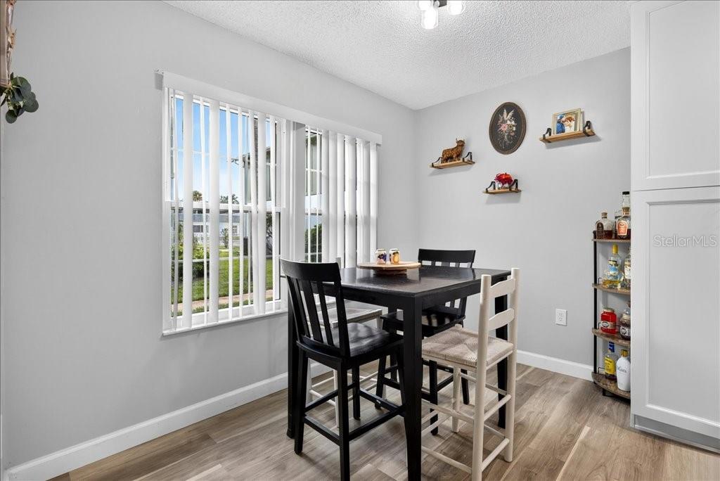 A dining area features a black table, mismatched chairs, a bar cart, and vertical blinds — 840 CENTER AVENUE UNIT 730, DAYTONA BEACH, FL