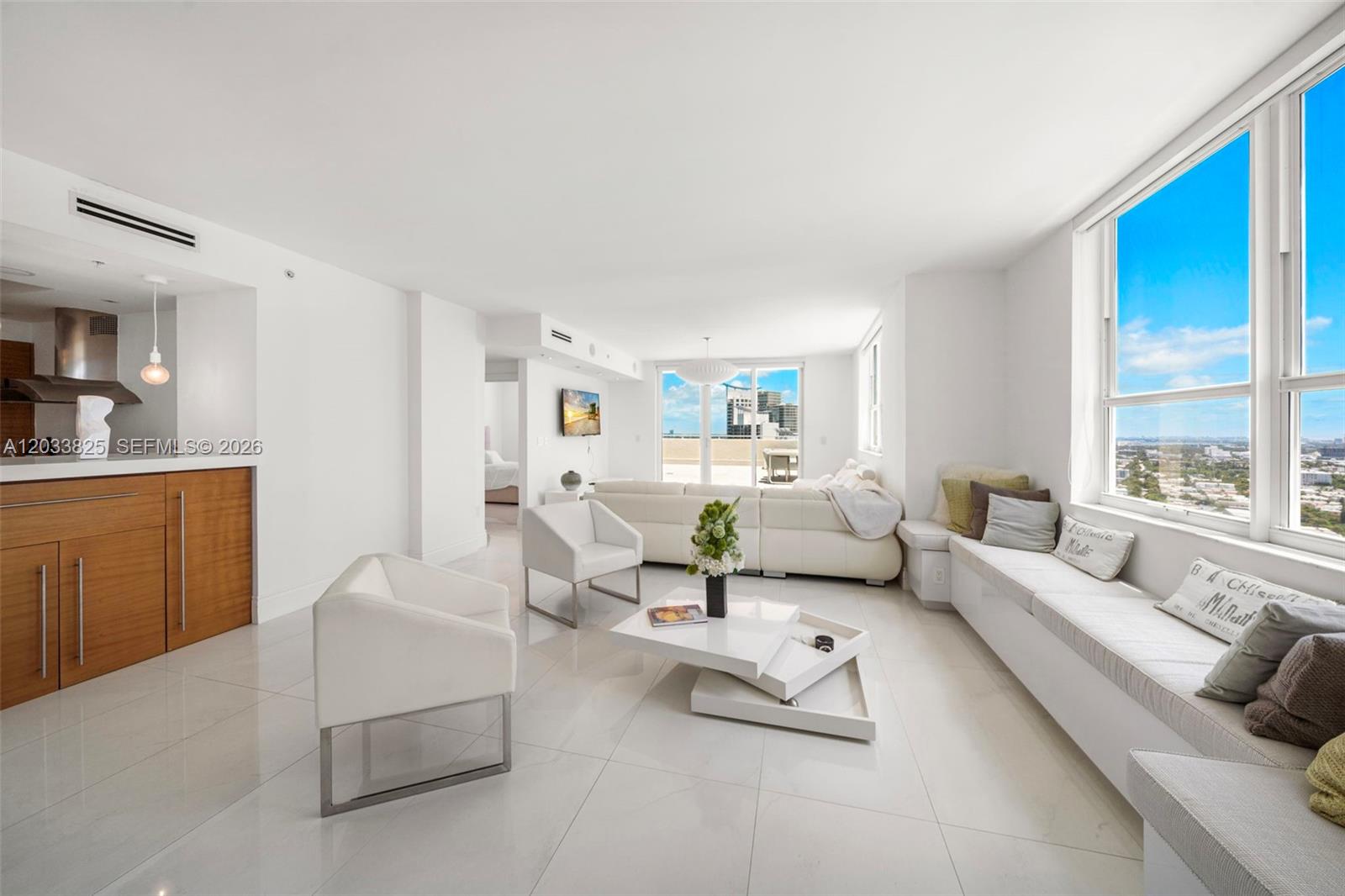 A bright living room features white tile floors, modern furniture, and a long window bench — 90 Alton Rd, Miami Beach FL 33139, MIAMI BEACH, FL