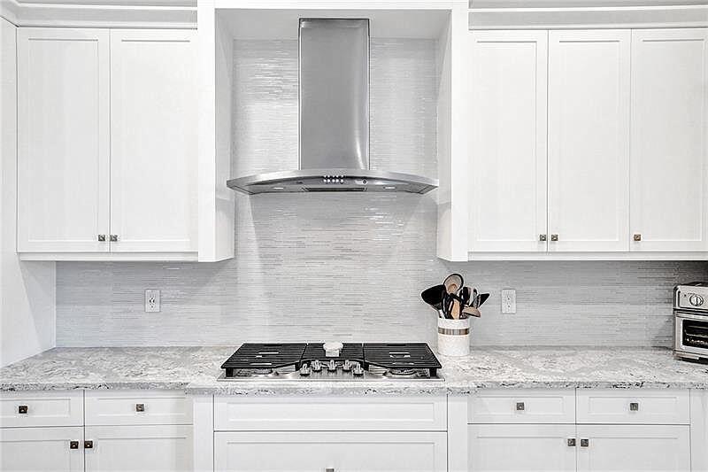 A modern kitchen features white cabinetry, a stainless steel range hood, and a granite countertop — 11720 Waterway Circle, Parkland FL 33076, PARKLAND, FL