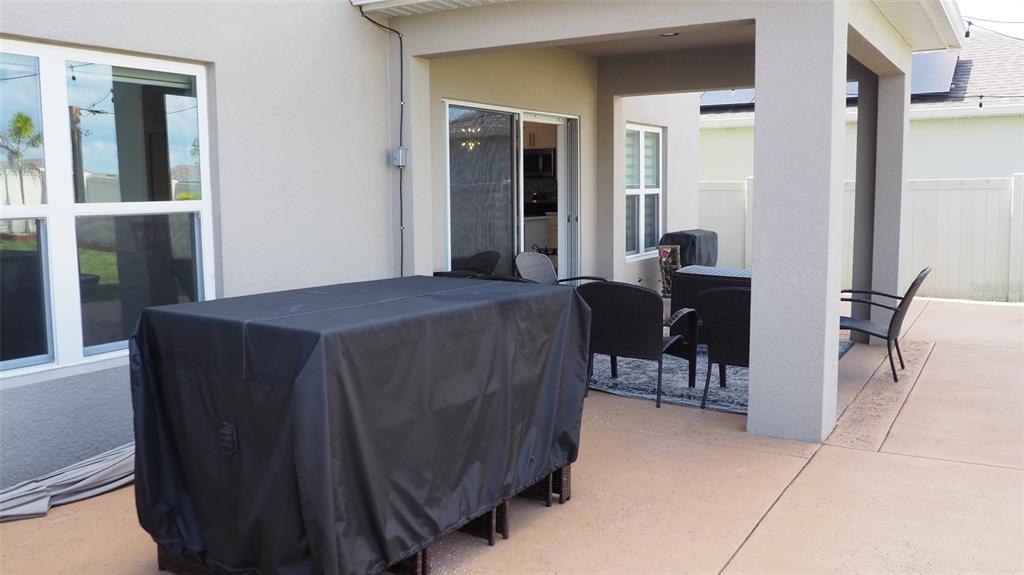 A covered patio features a dining table with a black cover and outdoor seating — 216 DENALI STREET, HAINES CITY, FL