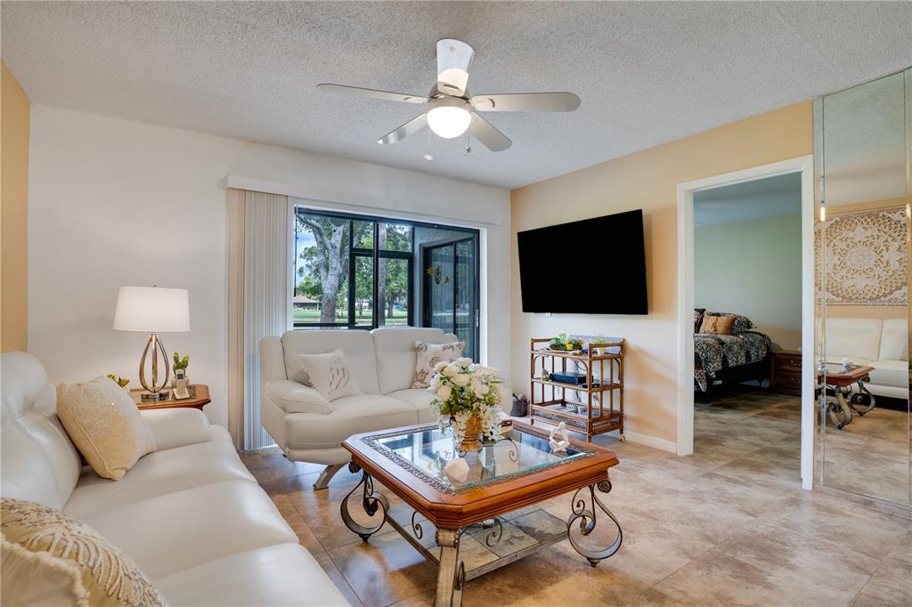 A living room features white leather sofas, a glass-topped coffee table, and a ceiling fan — 117 E CYPRESS COURT UNIT 117, OLDSMAR, FL