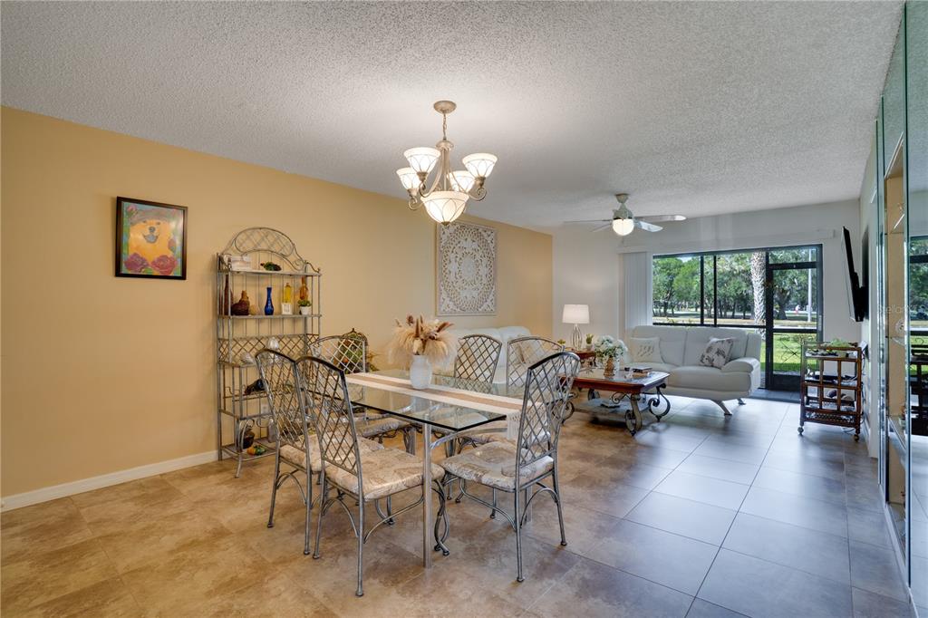 A dining area and living room with tile floors, a glass table, and sliding glass doors — 117 E CYPRESS COURT UNIT 117, OLDSMAR, FL