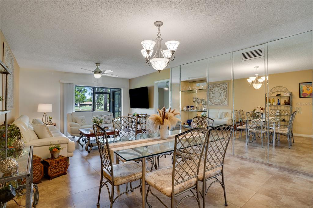 A dining and living area features tile floors, a glass table, and mirrored wall panels — 117 E CYPRESS COURT UNIT 117, OLDSMAR, FL