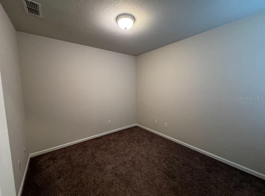 An empty room with beige walls, brown carpeting, and a central ceiling light fixture — 4401 SW 52ND UNIT 101, OCALA, FL