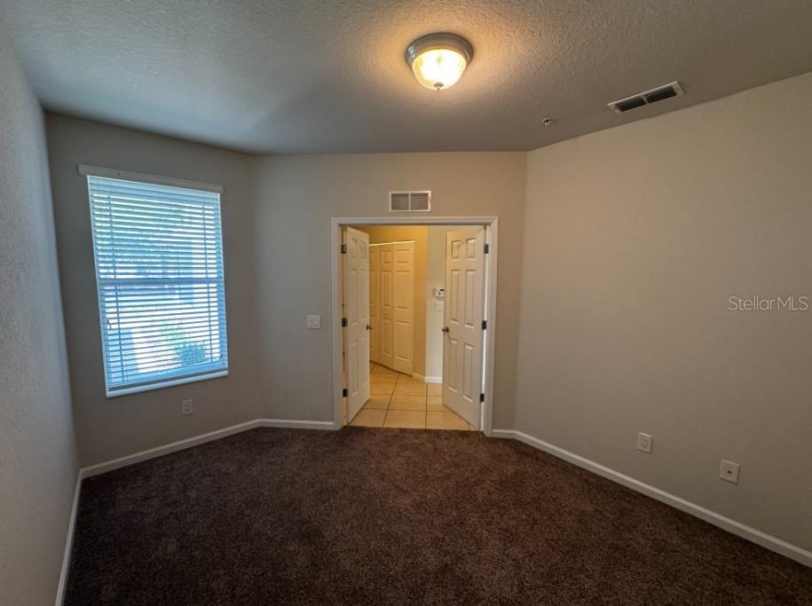 A carpeted room with a window, a ceiling light, and double doors leading to tile — 4401 SW 52ND UNIT 101, OCALA, FL