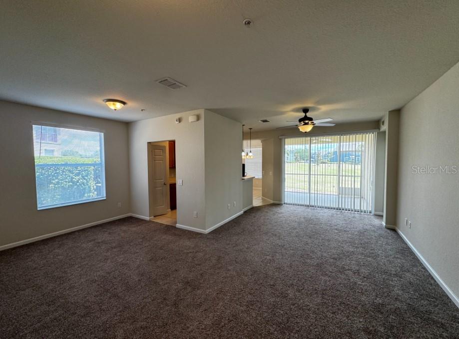 An open-concept living area features brown carpeting, a ceiling fan, and a sliding glass door — 4401 SW 52ND UNIT 101, OCALA, FL