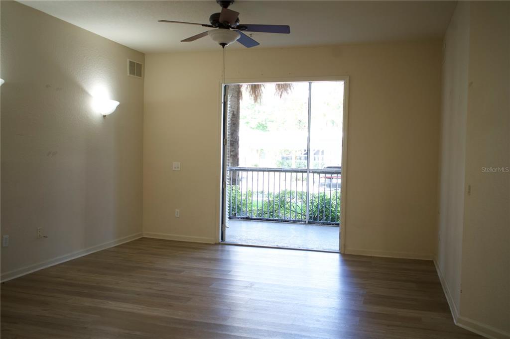 An empty room with light wood-look flooring, a ceiling fan, and a screened-in balcony — 3301 WHITESTONE CIRCLE UNIT 105, KISSIMMEE, FL