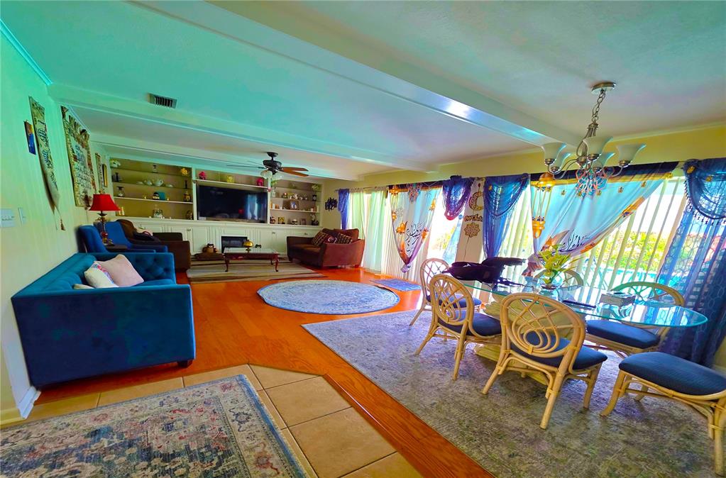 An open-concept living and dining area features hardwood floors, a blue sofa, and large windows — 805 S KEENE ROAD, CLEARWATER, FL