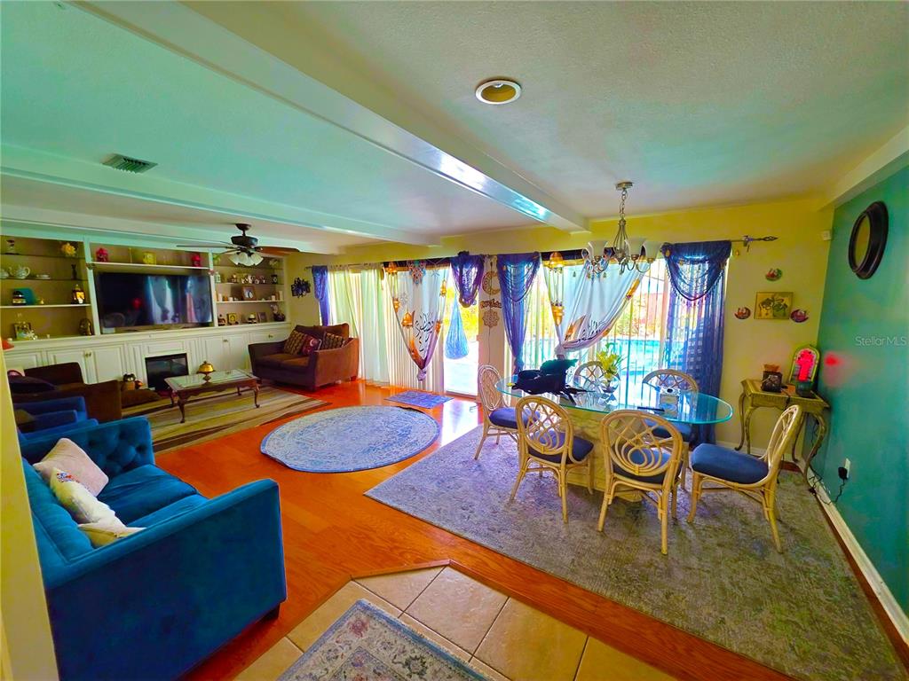 A living and dining room with hardwood floors, a blue sofa, and sliding glass doors — 805 S KEENE ROAD, CLEARWATER, FL