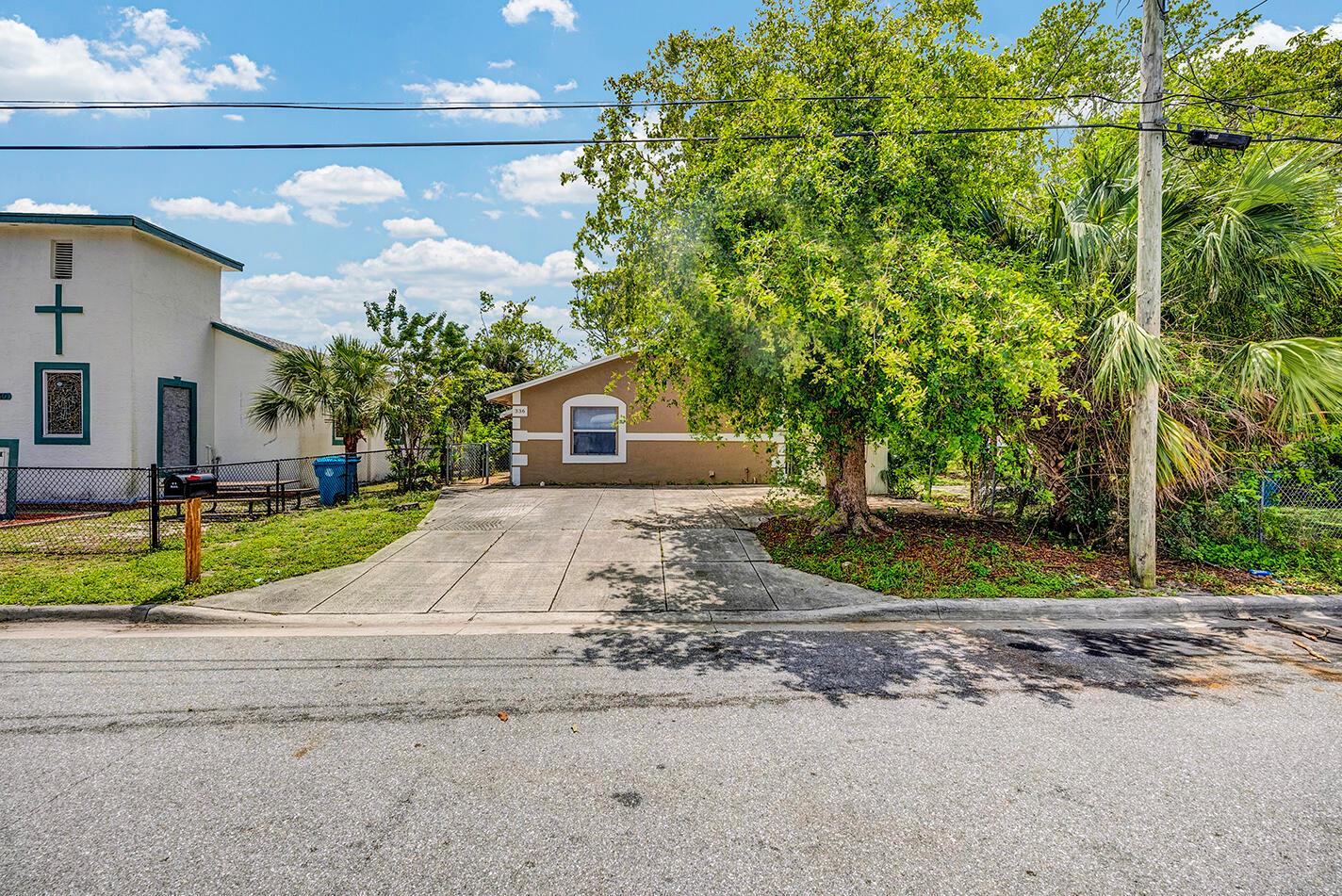 A tan single-story house with a concrete driveway sits behind a large tree — 336 NE 12th Avenue, Boynton Beach FL 33435, BOYNTON BEACH, FL